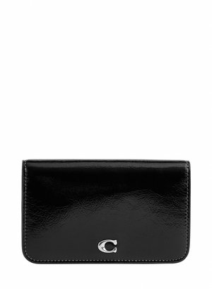 Portefeuille en cuir noir brillant avec un petit emblème argenté "C" centré sur le rabat avant, forme rectangulaire avec des coins arrondis.