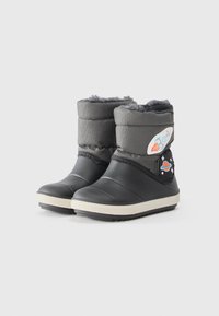 Bottes noires imperméables avec une tige texturée, doublure en fourrure et semelles en caoutchouc blanches. Présente des écussons colorés sur le thème de l'espace sur les côtés.