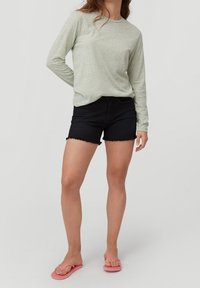 Light green long-sleeve top, black denim shorts with frayed hem, and pink flip-flops. The fabric appears soft with a casual fit.