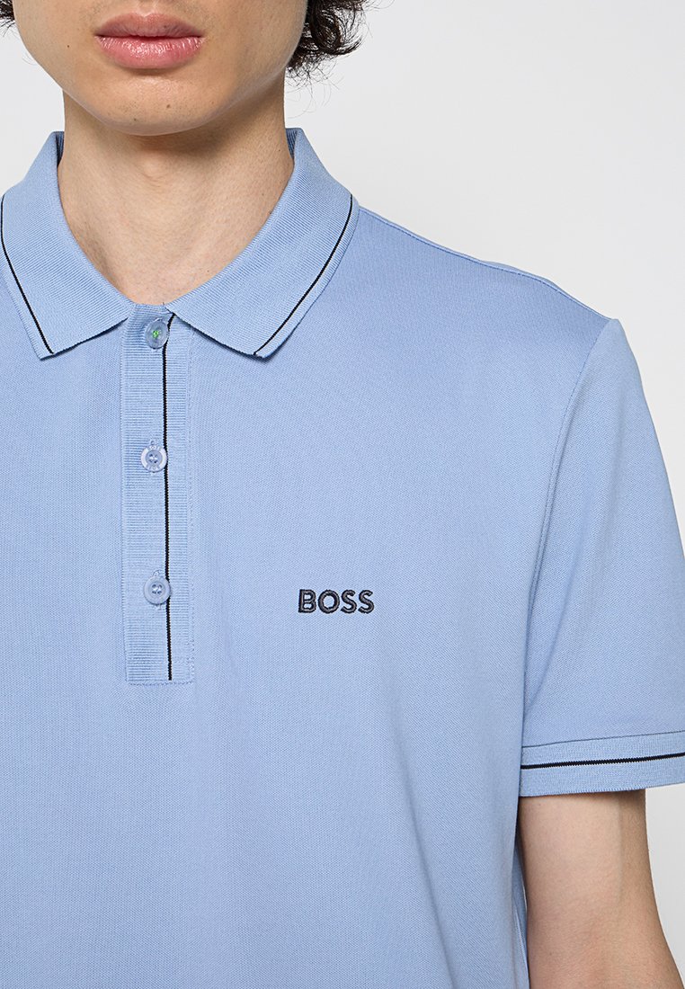 Hellblaues Polohemd mit Kragen, das schwarze Akzente entlang der Knopfleiste und der Ärmel aufweist, sowie ein kleines gesticktes "BOSS"-Logo.