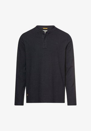 Chemise Henley noire à manches longues avec trois boutons au col, petit logo sur la poitrine et une étiquette jaune à l'intérieur du col.