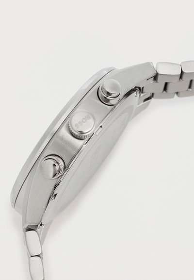 Vue latérale d'une montre-bracelet en acier inoxydable montrant deux boutons-poussoirs et une couronne gravée "BOSS" sur un bracelet métallique à maillons.