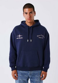 Navyblauwe capuchonsweater van zachte stof, met een voorzak. Inclusief witte en roze logo-details op de borst.