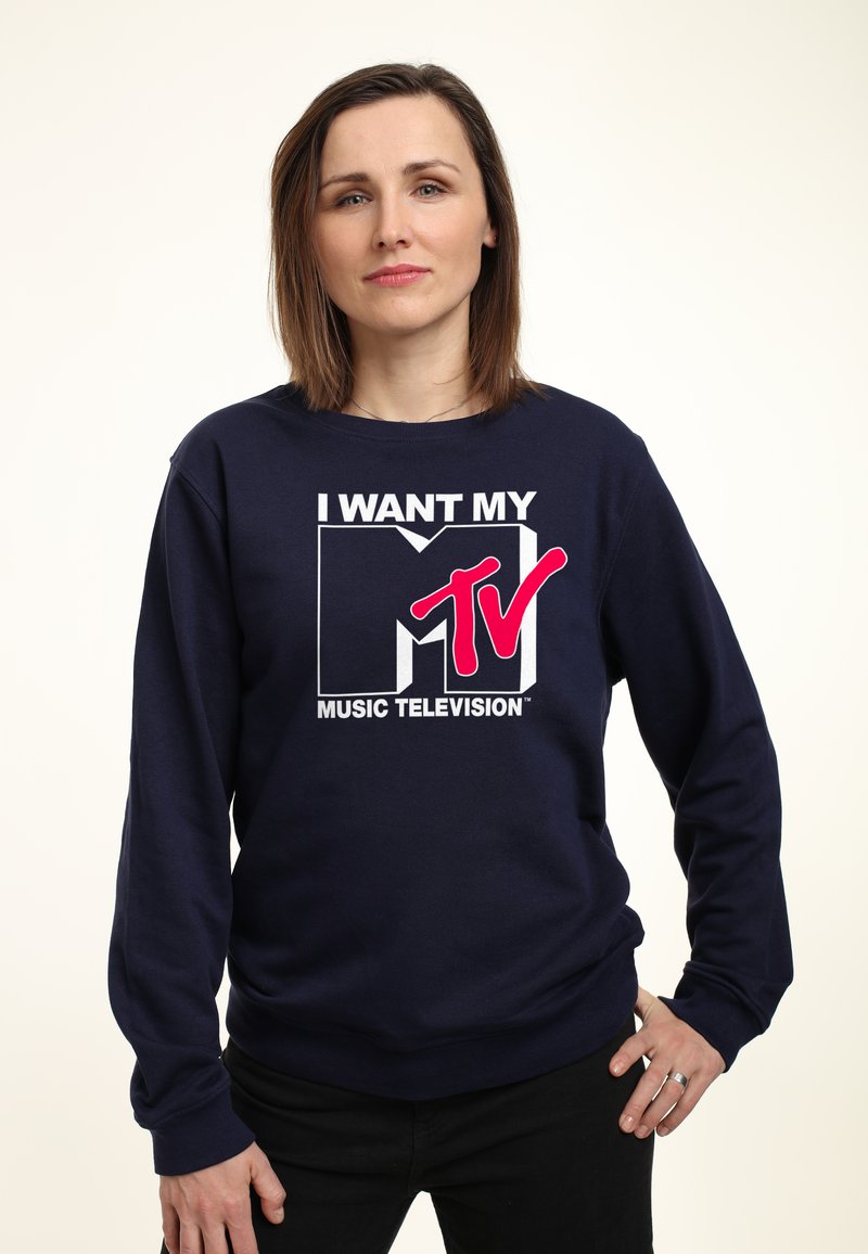 Marinblå sweatshirt med en djärv grafisk design som visar "JAG VILL HA MITT MTV" i vit och rosa text. Långa ärmar, rund hals och avslappnad passform.