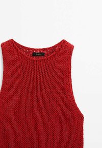 Haut sans manches rouge en tricot avec un col rond, un effet maille ajourée et une coupe légèrement ample. Étiquette visible au niveau du col.