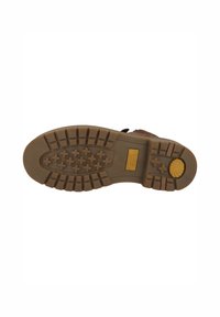 Suela de goma marrón con un patrón texturizado, que presenta surcos profundos y un acento amarillo cerca del talón. Se puede ver el texto "Camel Active".