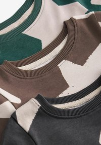 Drei Crewneck-Sweatshirts gestapelt: grün camoufliert, braun mit beigen Akzenten und dunkelgrau. Jedes verfügt über gerippte Kragen in passenden Farben.