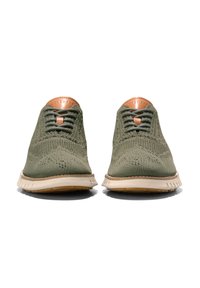 Zelené pletené tenisky s texturovaným svrškem, akcenty z tanové kůže a bílou podešví, se šněrováním vepředu a strukturovaným designem.