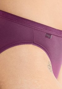 Pruimen kleurige slip met een zachte, gestructureerde stof. Kenmerkt zich door een scalloped tailleband en een klein logo label aan de zijkant.