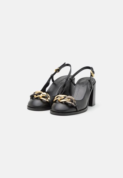 Black leather slingback heels with a chunky heel, featuring a decorative gold chain and snake-patterned accent on the front.