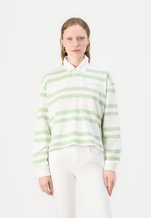 White long-sleeve polo shirt with green horizontal stripes, featuring a collar and embroidered logo on the chest, paired with white pants.