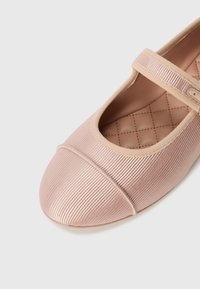 Ballerines en tissu rose avec une texture côtelée, bout rond et une sangle réglable sur le coup de pied. Détail de semelle intérieure matelassée et rembourrée.