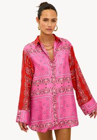 Roze en rode blouse met lange mouwen in een bandanapatroon, voorzien van een kraag, knoopsluiting en een losse pasvorm. Zachte stoftextuur.