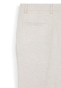 Close-up di pantaloni beige chiaro texturizzati che mostrano la parte posteriore della cintura, gli passanti per la cintura e il dettaglio di una tasca a filetto singola.