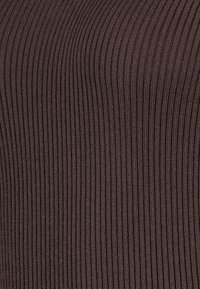 Braunes, geripptes Strickgewebe mit vertikalen Linien, das eine weiche Textur und eine enge Passform aufweist und sich für verschiedene Kleidungsstücke eignet.