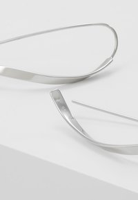 Occhiali da vista in metallo argentato con un design elegante, caratterizzati da montature sottili e una superficie liscia. Il nome del marchio "SKAGEN" è inciso sulla asta.