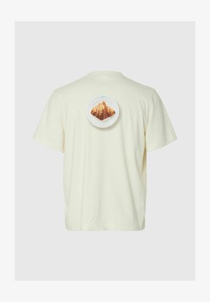 Off-white T-skjorte med en liten tallerken-grafikk med en croissant plassert sentralt på øvre del av ryggen.