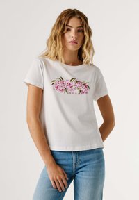 Λευκό βαμβακερό t-shirt με ροζ λουλουδένιο σχέδιο και πράσινα φύλλα, με τη λέξη "LONDON" στο κέντρο. Κοντά μανίκια, άνετη εφαρμογή.