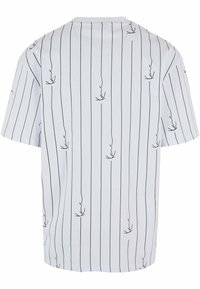 Bílý krátký rukáv tričko s vertikálními černými pruhy a jemným vzorem, které ukazuje uvolněný střih a hladkou texturu.