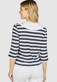 Gestreiftes Oberteil mit navyblauen und weißen horizontalen Streifen, drei Viertel Ärmeln und einem runden Ausschnitt. Verfügt über ein geschichtetes Design mit einem internen weißen Hemd.