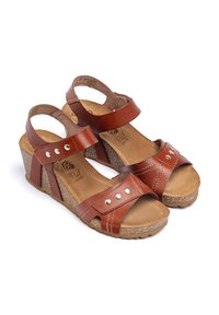 Bruine leren wedge sandalen met brede banden, nagelaccenten en een getextureerde kurken voetbed. Verstelbare enkelbandjes verbeteren de pasvorm en het comfort.
