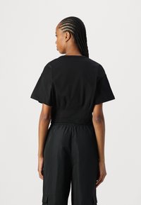 Svart kortärmad t-shirt med rund halsringning, tillsammans med svarta cargobyxor med elastisk midja och sidofickor.
