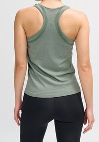 Green athletic tank top with a racerback design, featuring a textured pattern along the straps and a smooth finish. Paired with black leggings.