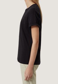 Černé bavlněné tričko s krátkými zatočenými rukávy, kulatým výstřihem a jemným logem vpředu. Jednoduchý střih s přímým střihem.