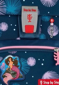 Marineblauwe rugzak met kleurrijke zee-thema patronen, voorzien van een zeemeermin patch, een roze rits en een grijs/rood sluiting met "Step by Step" merk.