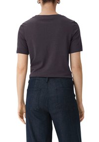 Czarnoszary t-shirt z krótkim rękawem o klasycznym okrągłym dekolcie, zestawiony z ciemnoniebieskimi spodniami dżinsowymi z tylnymi kieszeniami i prostym krojem.