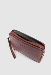 Portafoglio in pelle marrone con due scomparti con zip, superficie texturizzata e rivestimento interno a contrasto. Include un cinturino da polso rimovibile.