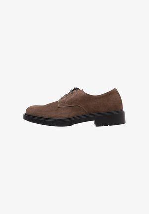 Chaussure en suede marron à lacets avec un bout arrondi, dotée d'une semelle en caoutchouc noir et de détails de couture subtils sur le côté supérieur.