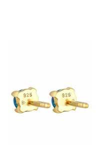 Boucles d'oreilles clous en forme de fleur plaquées or, avec des pierres précieuses bleues, gravées "925" à l'arrière, dotées d'un design de tige sécurisé.