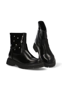 Botas de tobillo de cuero negro con un acabado brillante, con tachuelas plateadas en un lado, una cremallera lateral y una suela de goma negra gruesa.