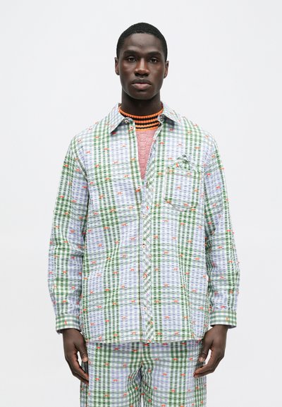 Πράσινο και λευκό πουκάμισο με καρό σχέδιο και πορτοκαλί λεπτομέρειες, με κουμπιά, τσέπη στο στήθος και άνετη εφαρμογή. Συνδυασμένο με παντελόνι σε παρόμοιο μοτίβο.