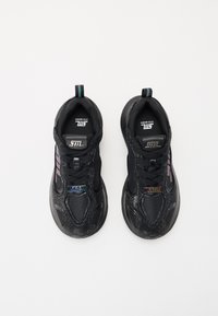 Adidași negri cu un superior din plasă texturată, talpă din cauciuc neted, accente irizate subtile și branding pe limbă și panourile laterale.
