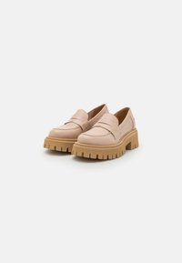 Loafer beige con una suola piattaformata spessa e texture. La parte superiore in pelle liscia presenta una banda rialzata sul davanti e dettagli di cucitura minimi.