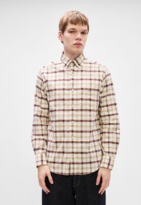 Camicia a maniche lunghe beige e marrone a quadri con colletto a punta. Presenta una tasca sul petto e chiusure a bottoni lungo la parte anteriore.