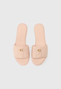 Light pink quilted slide sandals with a gold logo accent on the strap and a smooth sole. Features soft synthetic material for comfort.