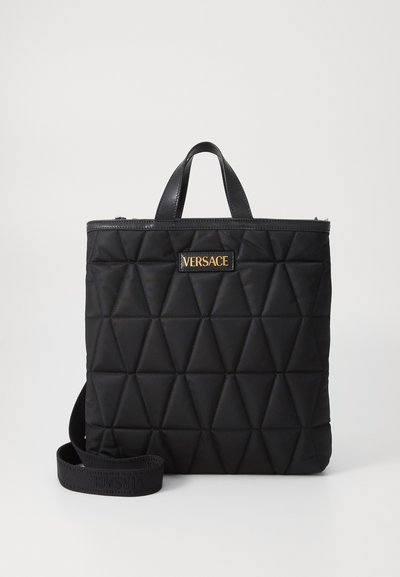 Borsa a tote in nylon trapuntato nero con motivi triangolari, rifiniture in cuoio, manici superiori e una tracolla staccabile con il logo dorato di Versace.