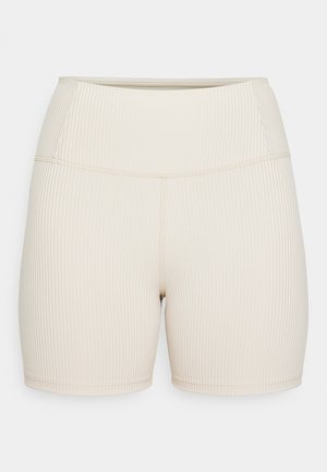 Shorts côtelés beiges avec une taille haute. Texture lisse, design ajusté et longueur mi-cuisse. Pas de matériel ou de motifs visibles.