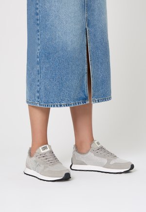 Zapatillas grises con diseño de materiales mixtos, que presentan malla y ante. Suela de goma rígida y puntera negra. Logotipo destacado en la lengua.