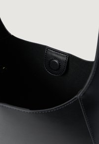 Sort skinnveske innside med en jevn tekstur, trykknapplås og et rent design uten ekstra mønstre eller detaljer.