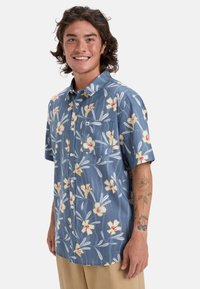 Hedvábná košile s krátkým rukávem, modrý květinový vzor, s žlutými a červenými květy na pruhovaném pozadí a náprsní kapsou.