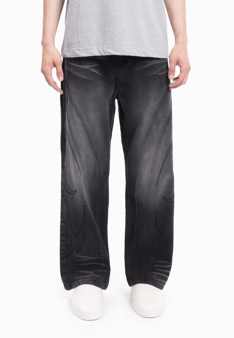 Jeans de ganga pretos de perna larga com padrões em relevo na frente, acabamento desbotado e detalhes subtis de costura.
