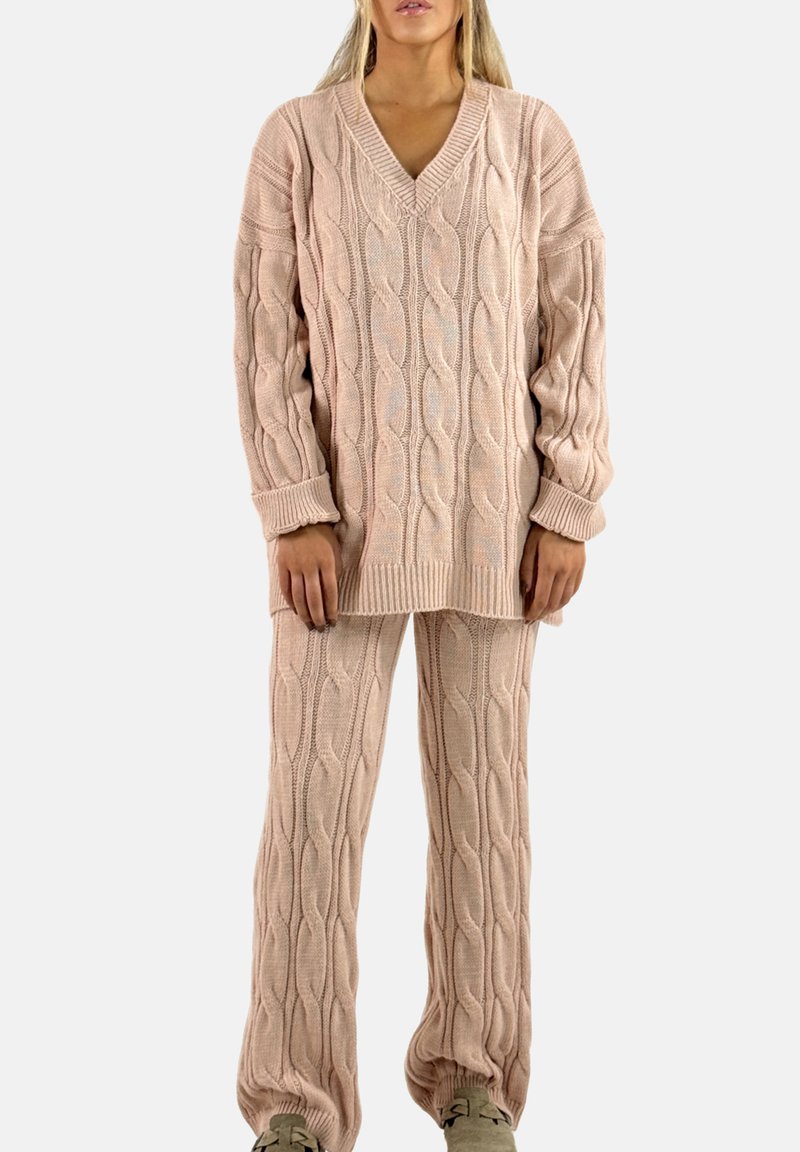 Loungewear-set met kabelgebreid patroon in lichtroze, bestaande uit een oversized trui met V-hals en bijpassende broek met geribbelde manchetten en een gestructureerd patroon.