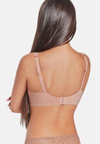 Soutien-gorge rose clair avec des bretelles ajustables, une texture lisse et une fermeture à crochets au dos. Design simple sans embellissements.