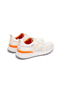 Zapatillas blancas con acentos grises y naranjas, que presentan una suela texturizada, parte superior de cuero suave y un forro interior contrastante.
