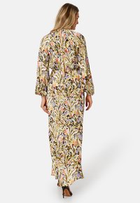 Robe maxi avec un imprimé floral en jaune, rose et violet sur un fond noir, dotée de manches longues et d'un détail d'ouverture au dos.