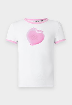 Bílá bavlněná tričko má růžový design ve tvaru srdce s klipsnou a textem "Polly Pocket", spolu s rukávy lemovanými růžovou barvou.